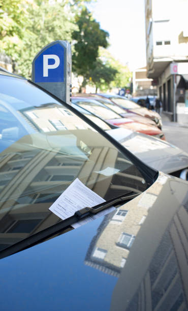 Vehicle fined for having parked in the blue zone. Ticket under the windshield wiper with parking meter at the bottom Vehicle fined for having parked in the blue zone. Ticket under the windshield wiper with parking meter at the bottom public service stock pictures, royalty-free photos & images