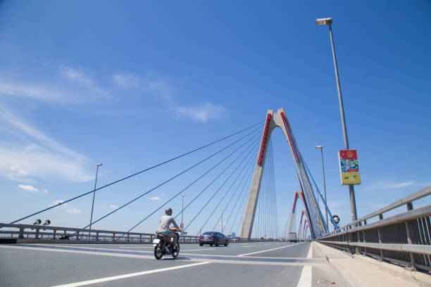 транспортные средства, путешествующие по мосту нхат тан через реку хонг (красный) - thich nhat hanh стоковые фото и изображения