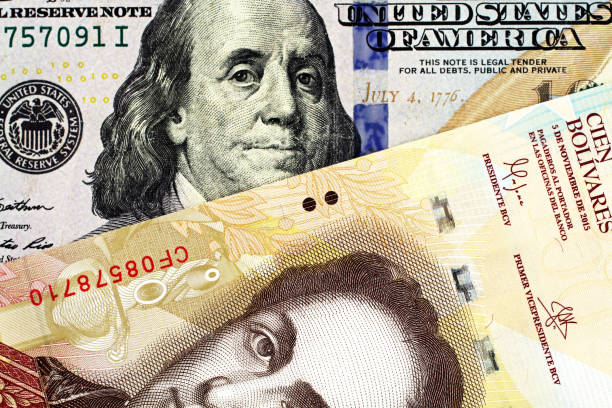 A Venezuelan one hundred Bolivar bank note with an American one hundred dollar bill close up stock photo