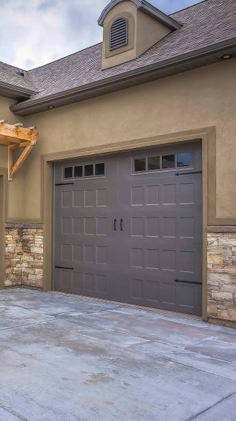 Vertical Exterior of a home with view of gray double garage doors and stone wall stock photo