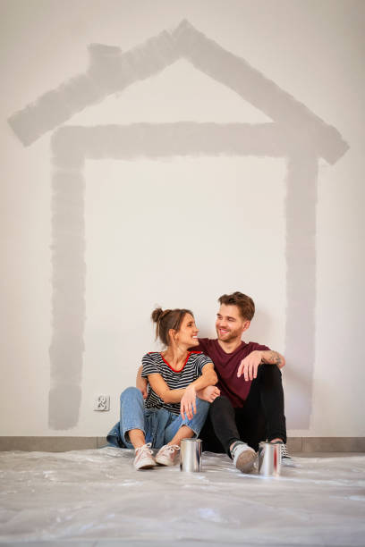 Vertical image of caucasian couple resting after wall painting of the new house stock photo