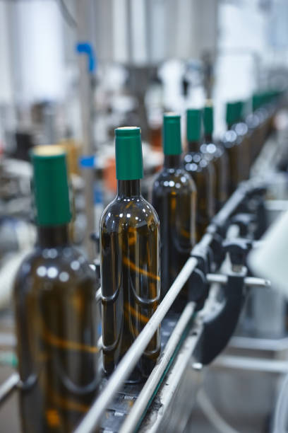 Vertical shot of a row of glass wine bottles moving by conveyor stock photo