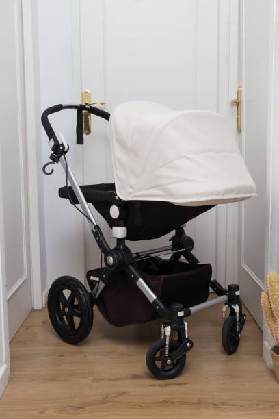 Vertical shot of a white and black baby carriage in the middle of two white doors stock photo