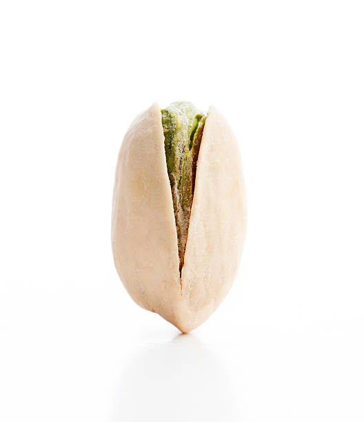 Vertical View of a Balanced Single Pistachio Nut Pistachio nut shown balancing in a vertical position on a white background pistachio stock pictures, royalty-free photos & images