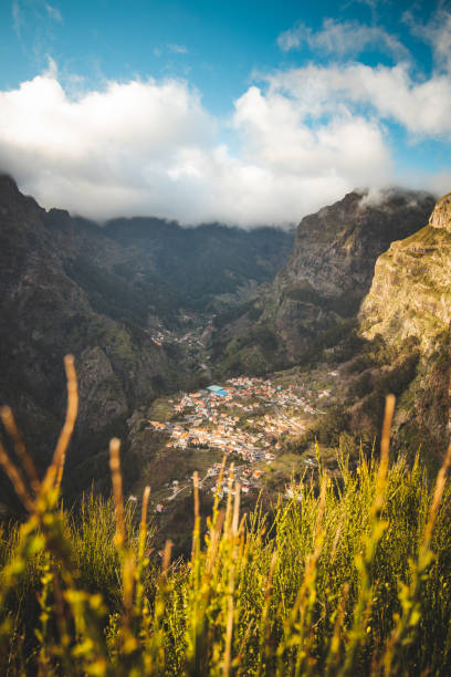 Very well-known tourist destination, Curral das freiras, a village nestled in the mountains with minimal sunlight. Aerial view of valley of nuns at sunset and peak of mountains in fog stock photo