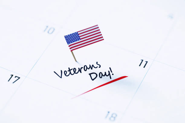 Veteran's Day Concept - Veteran's Day Note Pinned By Tiny American Flag On A White Calendar Veteran's Day note over white calendar pinned by tiny American flag to remind its importance. Calendar and reminder concept. Horizontal composition with copy space. High angle view. memorial day background stock pictures, royalty-free photos & images