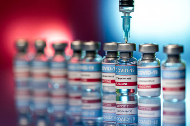 Vials and Syringe - Close up of Covid-19 vaccine on a reflective surface stock photo