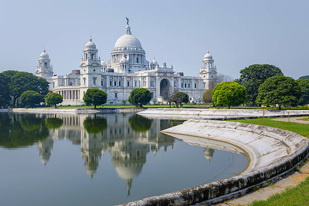 Victoria Memorial, Kolkata, India. The Victoria Memorial, white marble monument in memory of Queen Victoria, on a bright sunny morning with blue sky with reflections of the memorial in the water feature to the front of the monument. Kolkata, India. kolkata stock pictures, royalty-free photos & images