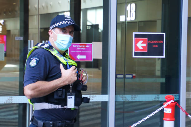 Victoria police officer wearing protective face mask at Covid-19 vaccination hub at Melbourne Convention Centre during lockdown in Victoria, Australia stock photo