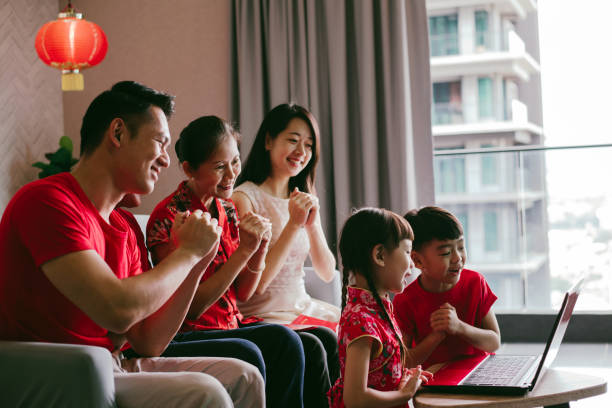 Happy Asian Chinese family making a video call on Chinese New Year taking to a relative far away using laptop.