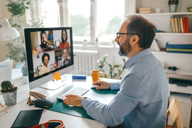 Video call with team members Businessman discussing work on video call with team members working from home stock pictures, royalty-free photos & images