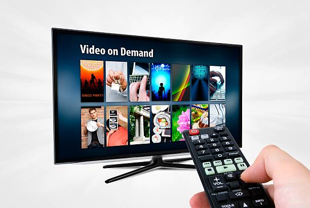 Video on demand VOD service on smart TV Video on demand VOD service on smart TV. Remote control in hand. video on demand stock pictures, royalty-free photos & images