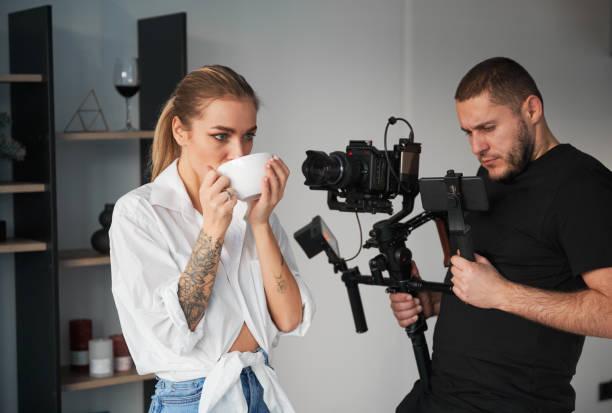 Videographer man shooting footage with female model, using camera. stock photo