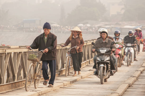 vietnamesen überqueren alte brücke am morgen. - motorrad fluss stock-fotos und bilder