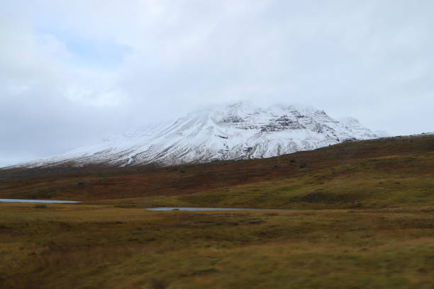 View from a car window while driving on a Road 95 (Skriddals- og Breiddalsvegur) in eastern Iceland. Snowcapped mountain in East Iceland stock photo