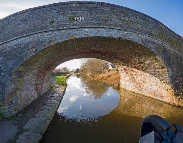 View of a British canal in rural setting with stone bridge stock photo