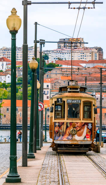 view of a typical street in the old town ribeira neighborhood with a classic retro tourist tram car in porto, portugal - carro oporto imagens e fotografias de stock