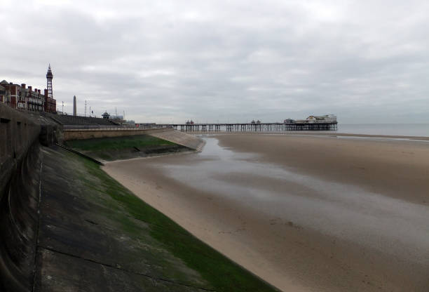 view of blackpool south pier and tower with beach at low tide with grey clouds view of blackpool south pier and tower with beach at low tide with grey clouds north pier stock pictures, royalty-free photos & images