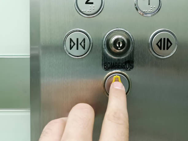 View of hand pressing emergency button on interior panel of an elevator stock photo