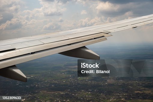 istock View of jet airplane wing landing at airport in bad weather. Travel and air transportation concept. 1352309633