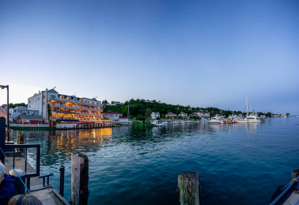 View Of Mackinac Island Marina And Town From The Ferry Dock At Sunset The lights of the little town of Mackinac shining as the evening faded on Mackinac Island mackinac island stock pictures, royalty-free photos & images