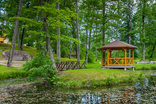 View of pond with small island of Love and wooden gazebo in the castle park. Tingere Manor, Latvia, Europe.