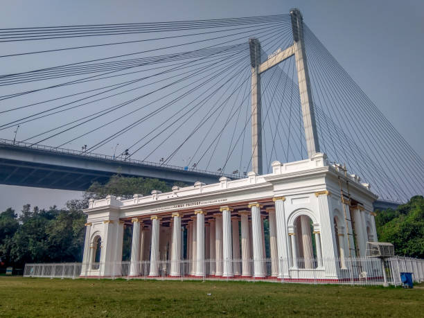 A view of Prinsep Ghat built in 1841 in memory of Anglo-Indian scholar James Prinsep with vidyasagar setu (bridge) in background. Kolkata, West Bengal / India - November 11 2019: A view of Prinsep Ghat built in 1841 in memory of Anglo-Indian scholar James Prinsep with vidyasagar setu (bridge) in background. ghat stock pictures, royalty-free photos & images