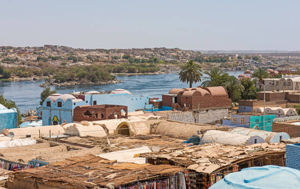 View of river nile in Aswan Egypt with Nubian village houses in foreground View of river Nile in Aswan Egypt from riverbank through rural countryside landscape with traditional Nubian village houses in foreground aswan egypt stock pictures, royalty-free photos & images
