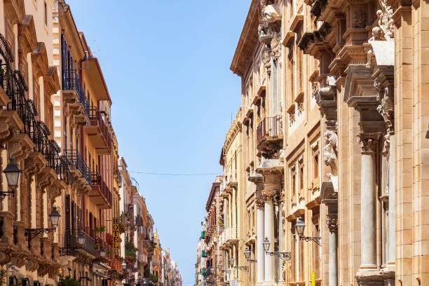 View of the apartments and businesses under a clear blue sky on a beautifully restored Trapini Sicily Street stock photo