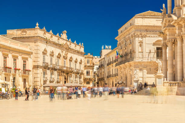 View of The Central Square in Ortygia (Ortigia, Piazza Duomo) with walking people. Historical buildings in the famous Sicilian town Syracuse (Siracusa), Italy stock photo