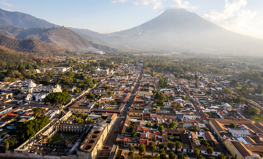 Drone view of the inactive Agua volcano, cobblestone streets and colonial houses in Antigua Guatemala on a sunny day