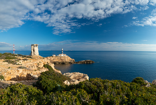 View of the lighthouse and the ruins of an old watchtower of the Majorcan pirate epoch and the silent seascape in the bay Cala Figuera in Calvia on the island Majorca. Composed Image with 8900px wide side. Color editing. Part of a series.