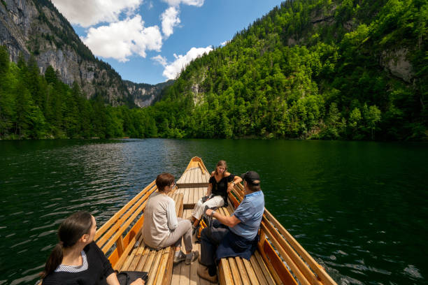 View of the prow of a "Plätte", a traditional wooden flat boat, navigating across the legendary Lake Toplitz, Ausseer Land region, Styria, Austria Toplitzsee, Austria - July 16th 2019: Tourists enjoying a boad ride on Lake Toplitz. The boat is a traditional Austrian wooden flat boat, called "Plätte" or "Plättl". ausseerland stock pictures, royalty-free photos & images