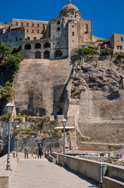 view of the seaside village of ischia ponte, tourists visiting the castle aragonese already fortress, prision and monastery of the ischia island, bay of naples italy - prision imagens e fotografias de stock