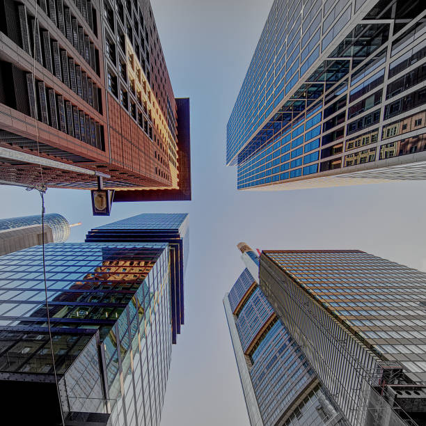 View of the small piece of free blue sky between four towers of high skyscrapers upwards stock photo