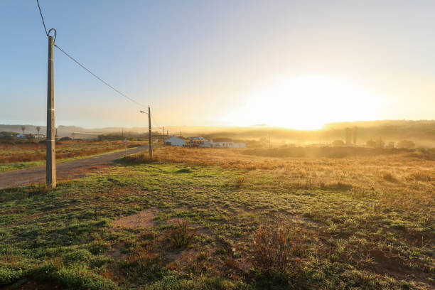 View of typical Alentejo landscape with Portuguese village in morning fog an rising sun at the Rota Vicentina hiking trail near Carrascalinho, Aljezur, Algarve and Alentejo area in Portugal stock photo