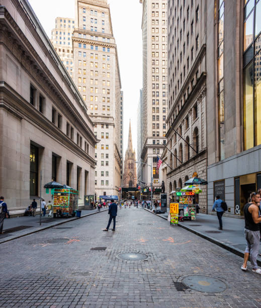 View of Wall Street vith people, and the Trinity Church in the background stock photo