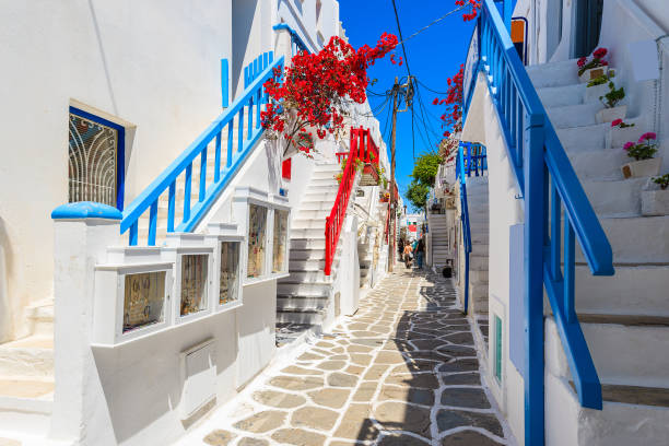 A view of whitewashed street with blue windows and flowers in beautiful Mykonos town, Cyclades islands, Greece stock photo