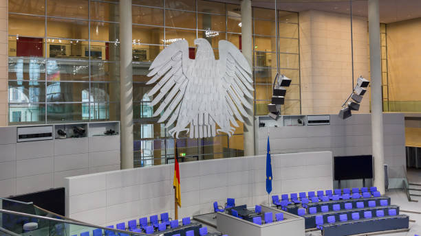 View on interior of the empty plenary hall of the German Federal Parliament (Deutscher Bundestag). Berlin, Germany - Jan 9, 2020: View on interior of the empty plenary hall of the German Federal Parliament (Deutscher Bundestag). In the middle the german coat of arms (eagle, so-called Bundesadler). Originally built by Paul Wallot, redesigned by Sir Norman Foster. Re-opened in 1999. bundestag stock pictures, royalty-free photos & images