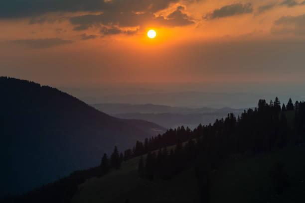 View over the mountains forests and alps at the Jenbach valley near Bad Feilnbach to the Bavarian Alpine foothills and the sunset, Bavaria, Germany stock photo