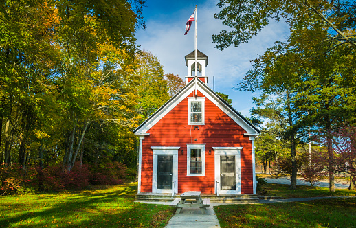 A bright red little one room school house on a fall afternoon