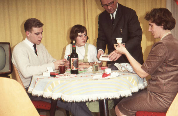 vintage jaren 1950 afbeelding: familie vieren sint nicolaas (sinterklaas) door het uitpakken van geschenken aan de eettafel. - sinterklaas cadeaus stockfoto's en -beelden