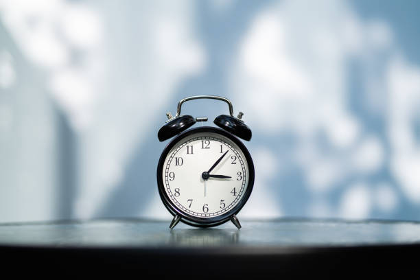 Vintage alarm clock at 3 o'clock with shadow background stock photo