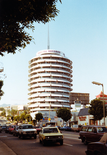 Los Angeles, CA, USA, 1989, Vintage analog view of the Capitol Records building in Los Angeles, California. Capitol Records is an American record label owned by Universal Music Group through its Capitol Music Group imprint. It was founded as the first west coast-based record label of note in the United States in 1942 by Johnny Mercer, Buddy DeSylva, and Glenn E. Wallichs. Capitol was acquired by British music conglomerate EMI as its North American subsidiary in 1955.