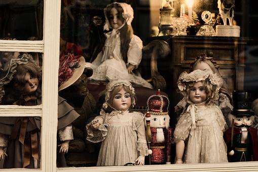 Indiana, USA - December 5, 2015: A window display of vintage antique dolls and Nutcracker dolls stare out as passering shoppers during Christmas season in the small town of New Harmony