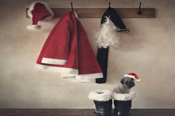 ein vintage-hintergrund von santa claus kostüm hängen an haken und ein mops, trägt einen roten hut sitzt in santas boot. - nikolaus stiefel stock-fotos und bilder