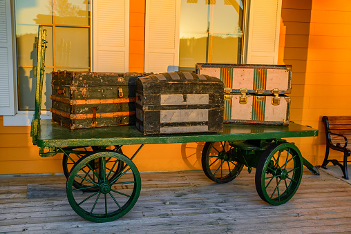 Three vintage baggage containers sit atop a green vintage wagon.