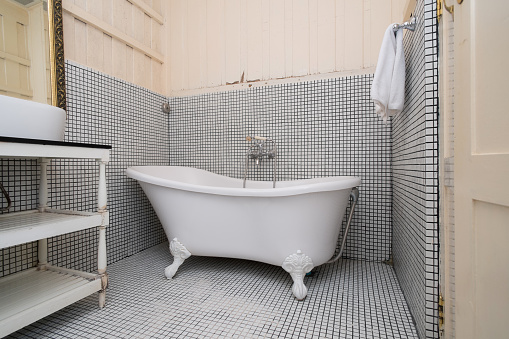 Classic vintage bath tub in colonial style bathroom with towel and wooden wall
