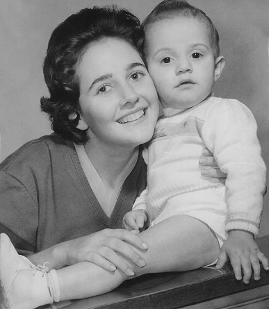 Vintage black and white image taken in 1960 of a caucasian Young woman posing with her one year old child boy