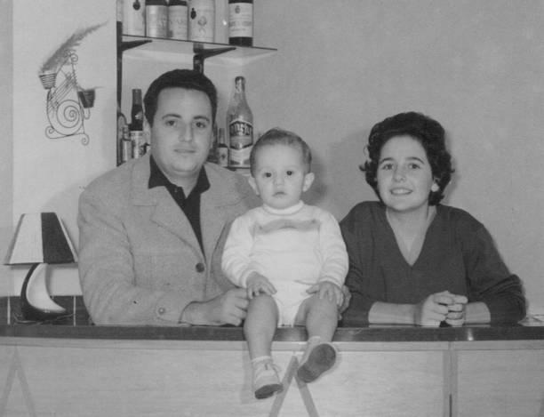 復古黑白照片拍攝於60年代，一個年輕男子和一個年輕女子與他們蹣跚學步的兒子孩子擺姿勢 - vintage 圖片 個照片及圖片檔